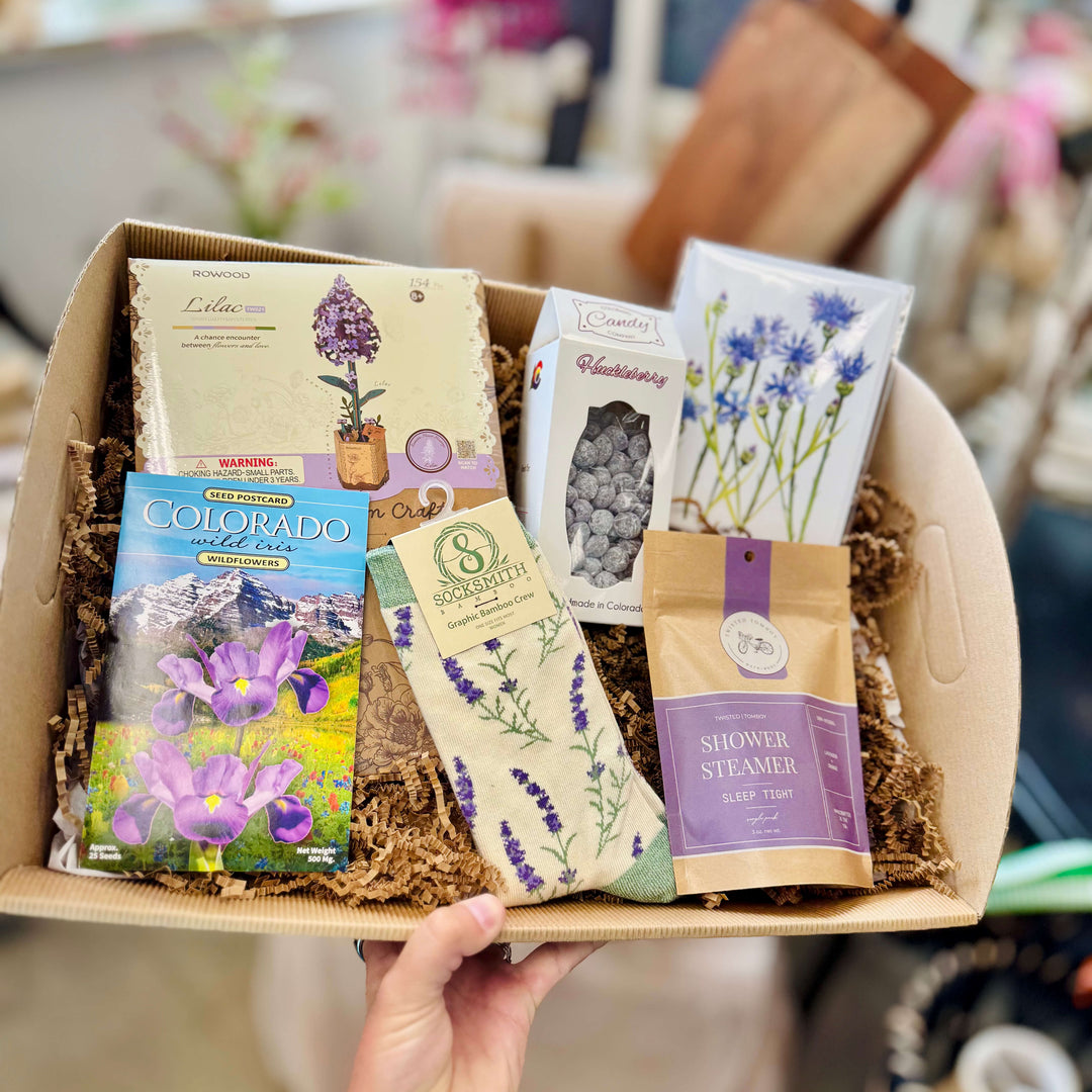  lavender and garden themed Mother's day gift box featuring flower seeds, shower steamers, artisan candy, cozy items, and a hand painted card 